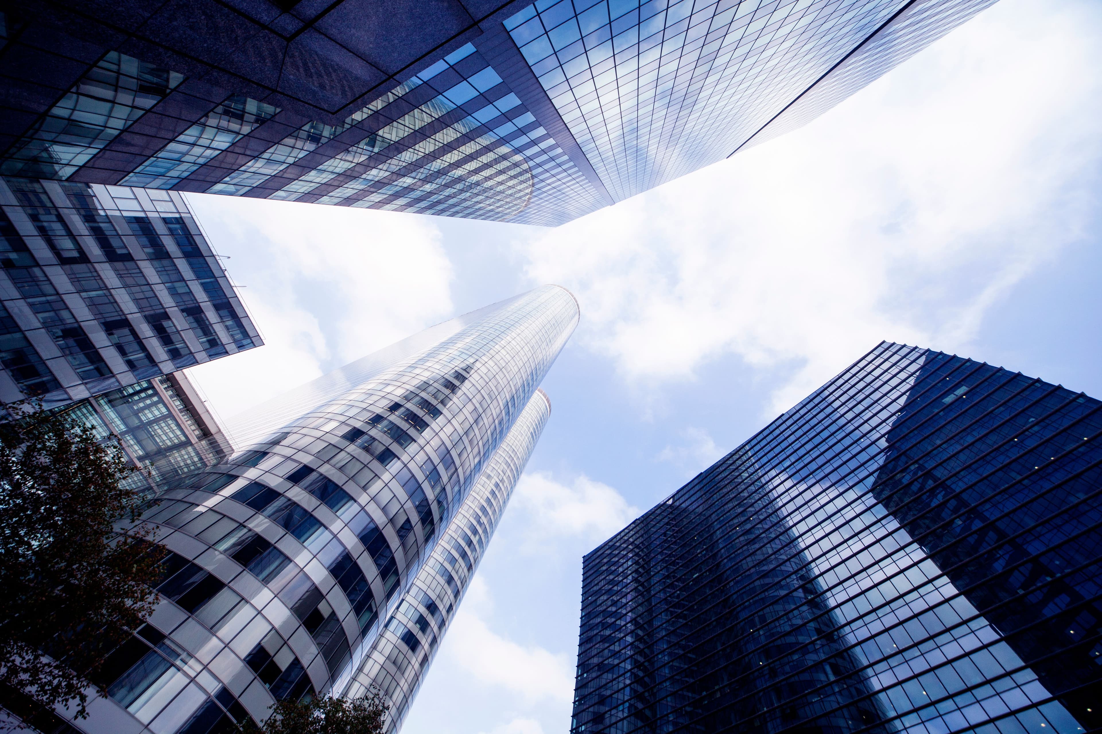 Glass office towers seen from below against a cloudy sky