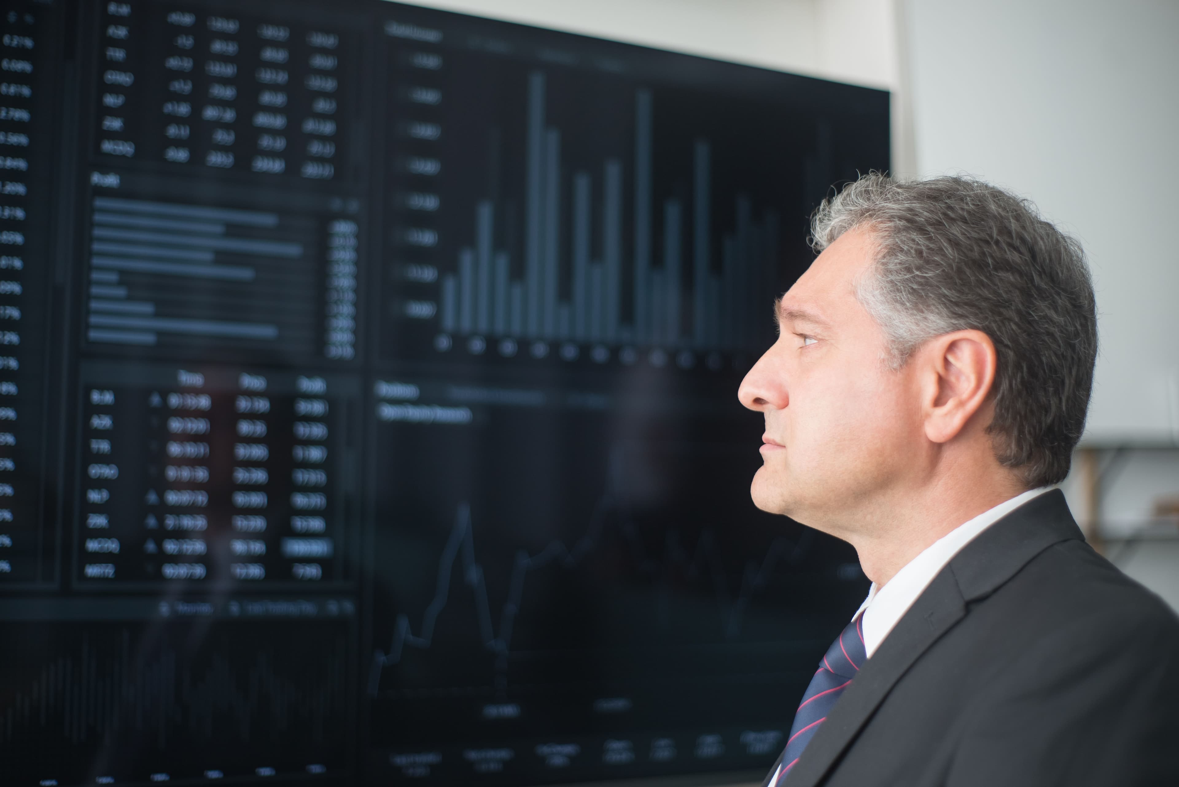 Executive studying a large screen of financial charts and tables