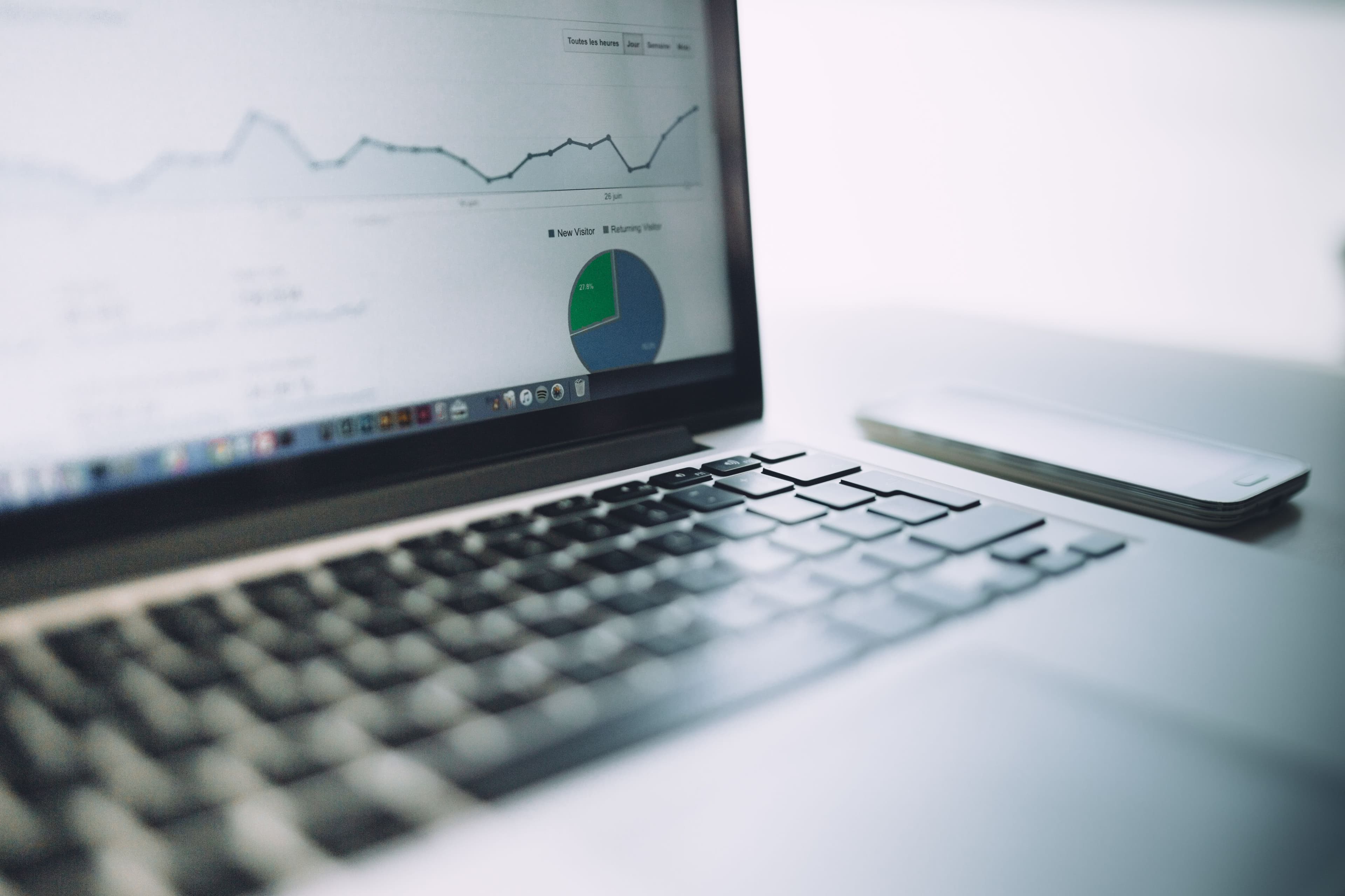 Laptop on a desk showing an analytics line chart and pie chart