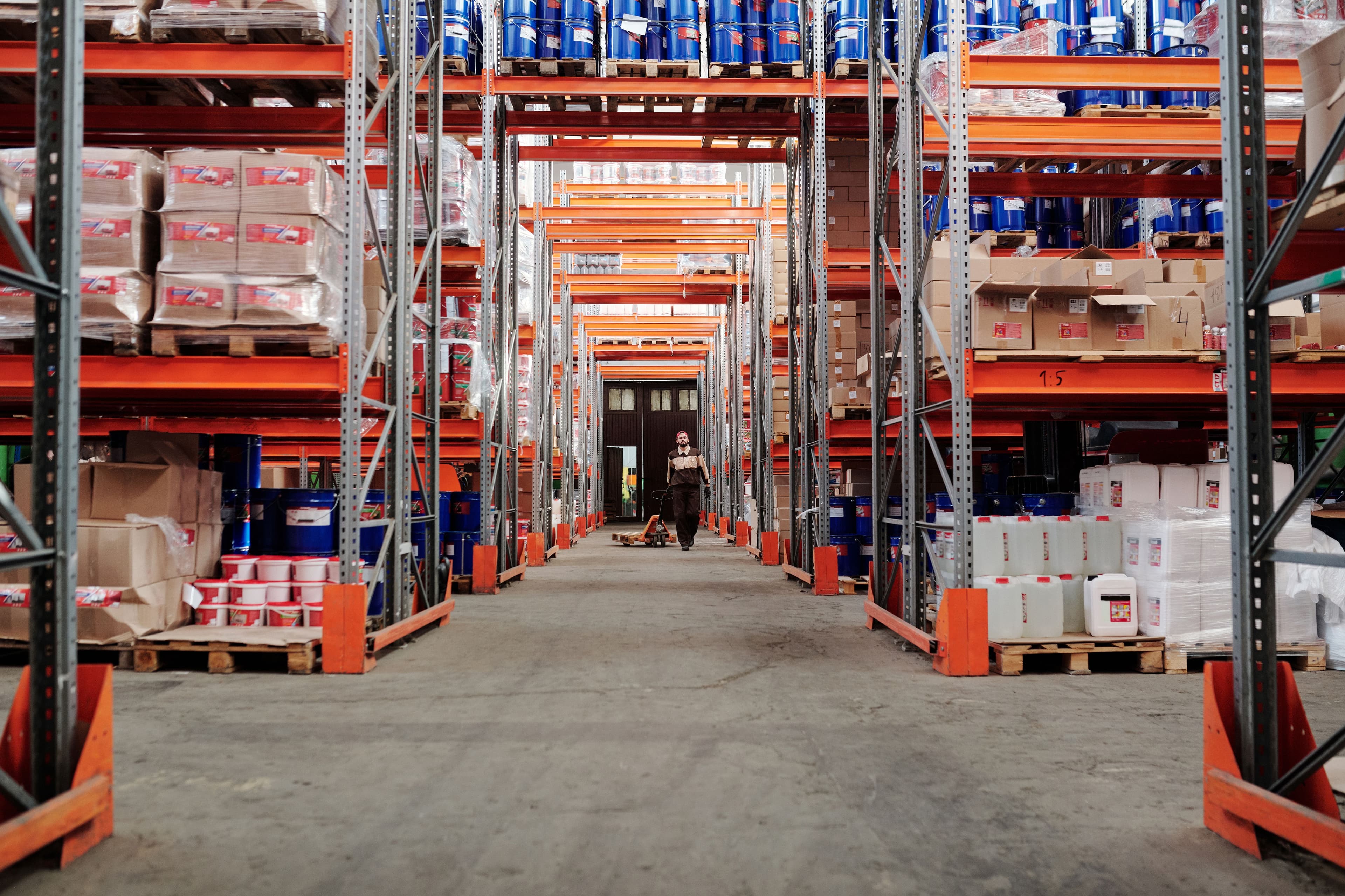 A warehouse worker moving inventory past tall storage racks
